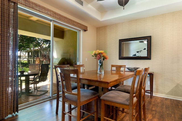 dining room featuring baseboards, visible vents, dark wood finished floors, a ceiling fan, and a raised ceiling