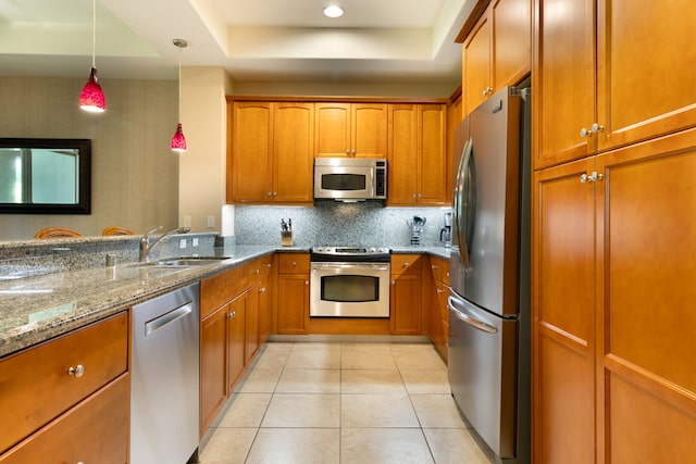 kitchen with appliances with stainless steel finishes, brown cabinetry, stone countertops, and a sink