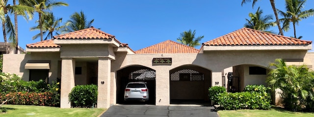 mediterranean / spanish-style home with concrete driveway, a tiled roof, and stucco siding