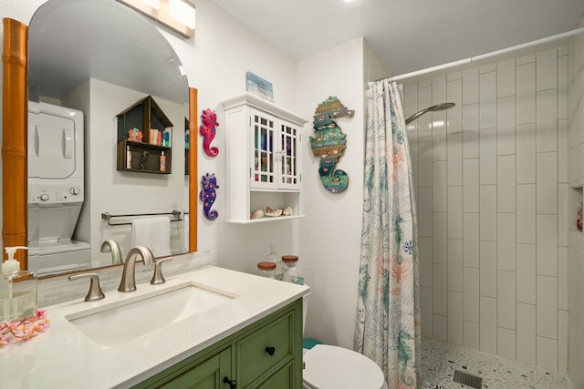 bathroom with tiled shower, vanity, toilet, and stacked washer / drying machine