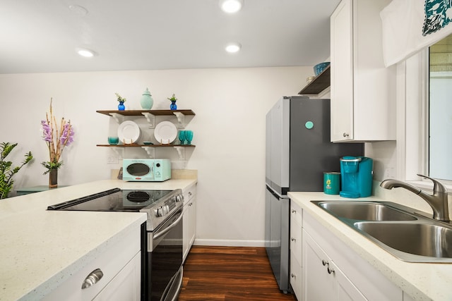 kitchen with white microwave, range with electric stovetop, a sink, and white cabinetry