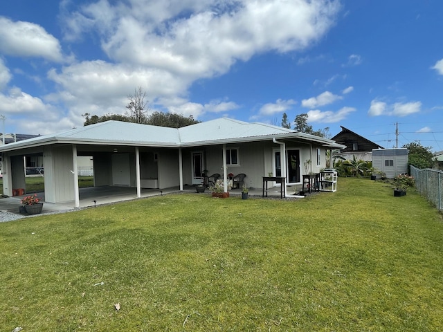 rear view of house featuring a shed, a patio, and a lawn