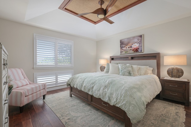 bedroom with a tray ceiling, wood finished floors, and a ceiling fan