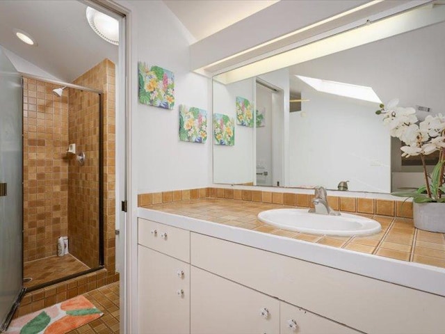 bathroom featuring a shower stall, vanity, and vaulted ceiling