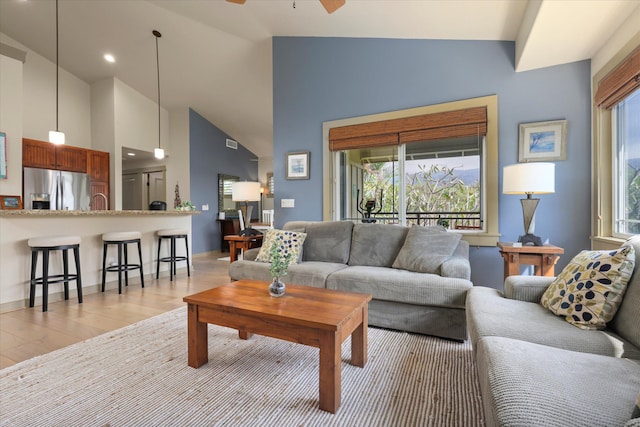 living room with high vaulted ceiling, light hardwood / wood-style flooring, and ceiling fan