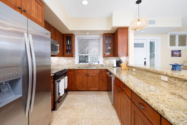 kitchen featuring light tile patterned flooring, decorative light fixtures, stainless steel appliances, light stone countertops, and tasteful backsplash