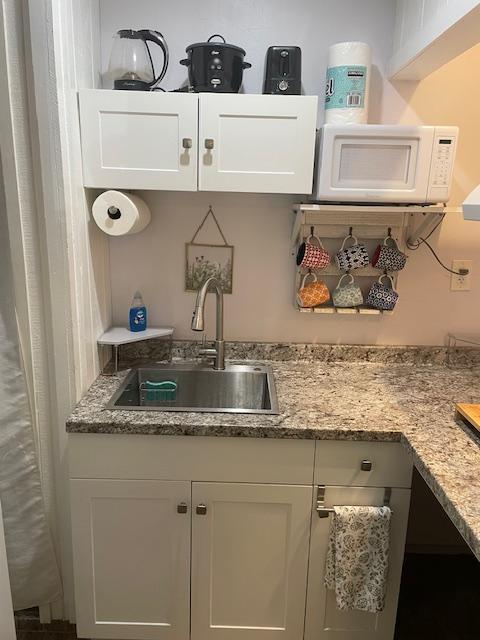 kitchen with sink, white cabinetry, and light stone countertops