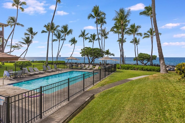 community pool with a water view, a yard, a patio, and fence