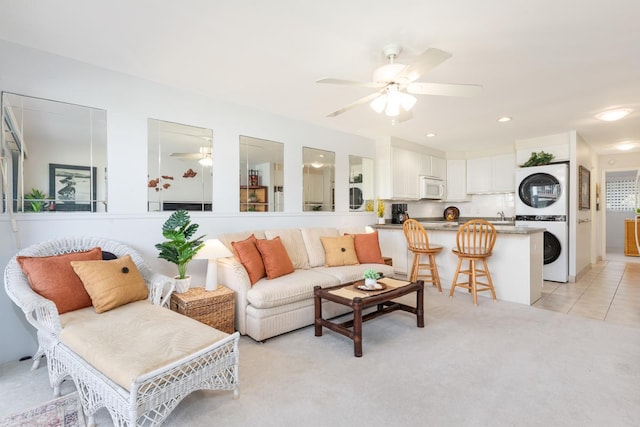 living room with recessed lighting, light colored carpet, a ceiling fan, light tile patterned flooring, and stacked washing maching and dryer