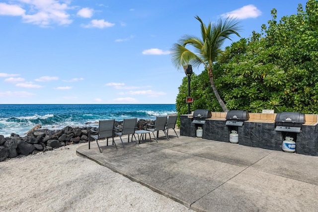 view of patio featuring a water view, a beach view, grilling area, and area for grilling