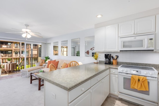 kitchen with ceiling fan, a peninsula, white appliances, white cabinets, and decorative backsplash