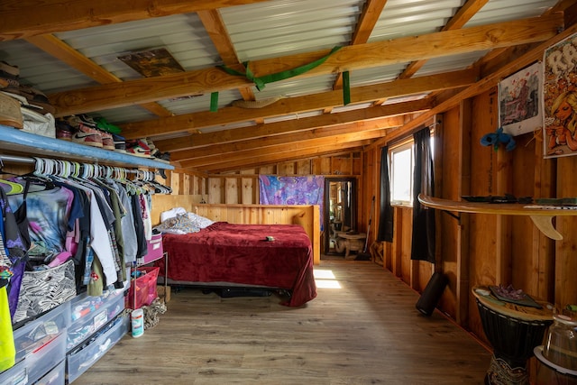 bedroom featuring vaulted ceiling, wooden walls, and wood finished floors