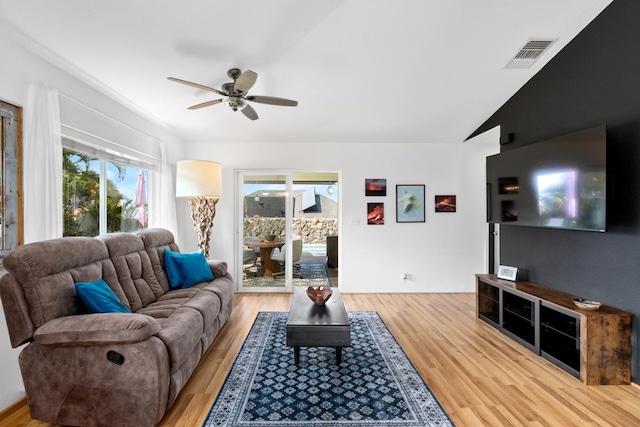 living room featuring lofted ceiling, light wood finished floors, ceiling fan, and visible vents