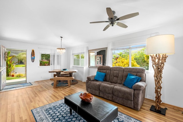 living area featuring light wood finished floors and ceiling fan with notable chandelier