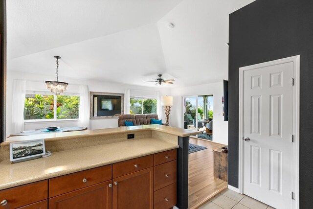 kitchen with light tile patterned floors, open floor plan, light countertops, brown cabinetry, and pendant lighting