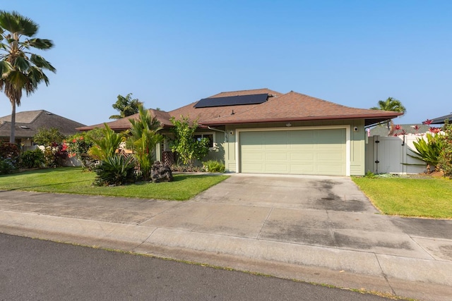 view of front of home with solar panels, an attached garage, a gate, driveway, and a front lawn