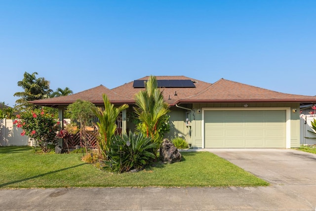 view of front of home with a garage, concrete driveway, solar panels, fence, and a front yard