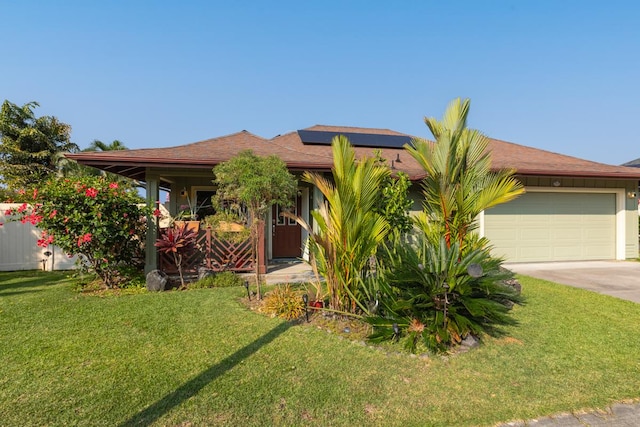 view of front facade featuring a garage, driveway, a front lawn, and solar panels