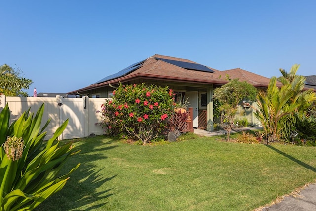 view of front of property with a gate, fence, solar panels, and a front yard