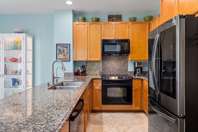 kitchen with light tile patterned floors, stone countertops, a sink, black appliances, and tasteful backsplash