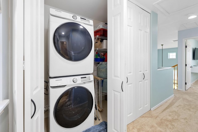 laundry area with stacked washer and dryer, laundry area, attic access, baseboards, and light colored carpet