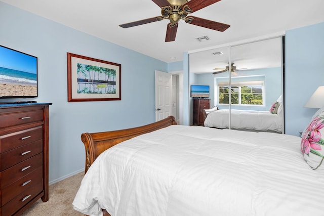 bedroom featuring a ceiling fan, a closet, visible vents, and light colored carpet