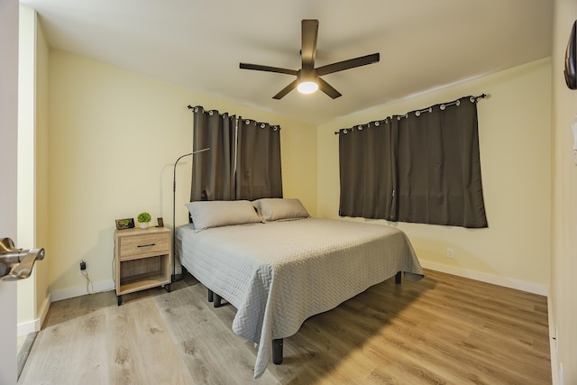 bedroom featuring baseboards, light wood-style floors, and ceiling fan