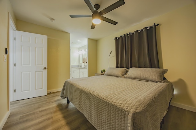 bedroom featuring ceiling fan, ensuite bathroom, light wood-type flooring, and baseboards