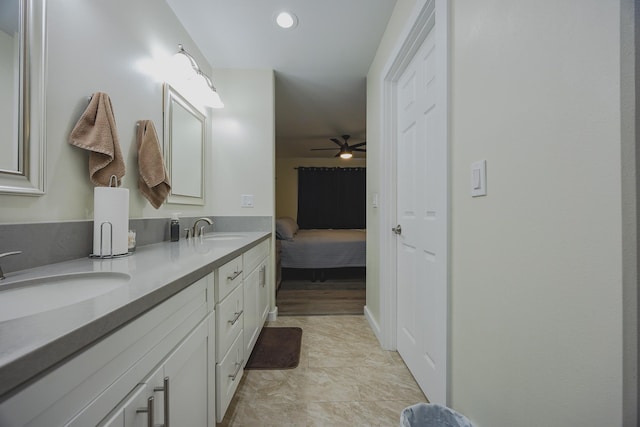 ensuite bathroom featuring ceiling fan, double vanity, ensuite bath, and a sink