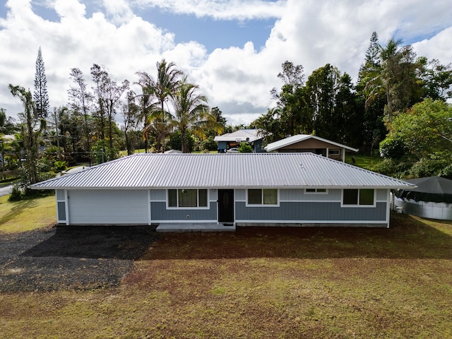 view of front of house with metal roof, driveway, a front lawn, and an attached garage