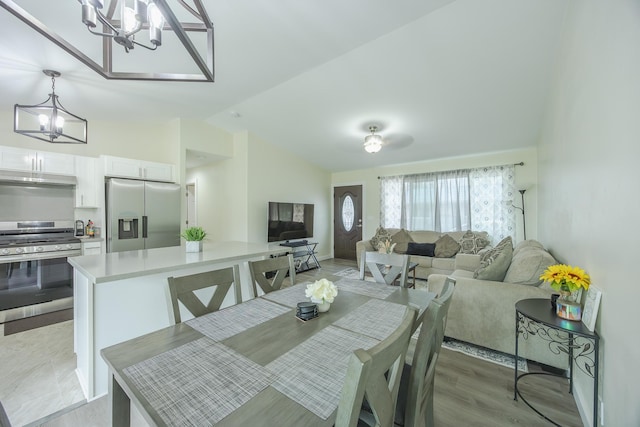 dining space with vaulted ceiling, light wood finished floors, and a chandelier