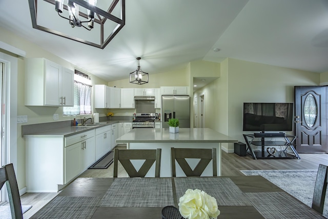 kitchen featuring a kitchen island, wood finished floors, white cabinetry, appliances with stainless steel finishes, and lofted ceiling