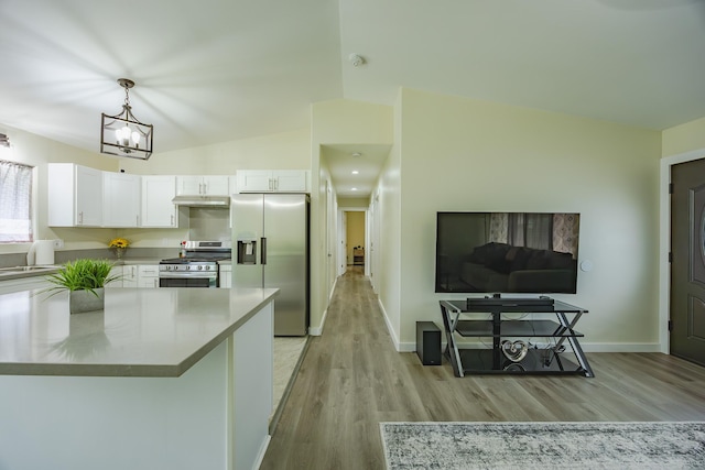 kitchen featuring light wood finished floors, vaulted ceiling, white cabinets, under cabinet range hood, and appliances with stainless steel finishes