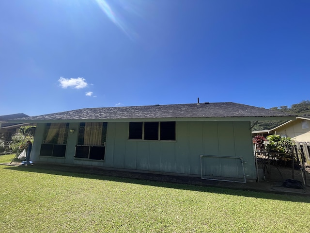 back of property with roof with shingles, a lawn, and board and batten siding