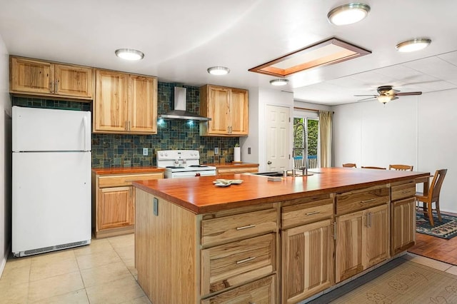 kitchen with wooden counters, a sink, a kitchen island, white appliances, and wall chimney exhaust hood