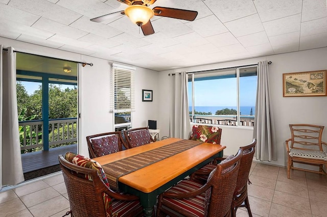 dining area featuring light tile patterned floors, a water view, and a ceiling fan