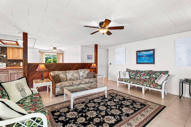 living area with ceiling fan, wooden walls, and light tile patterned flooring