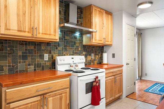 kitchen with light tile patterned floors, white electric stove, decorative backsplash, wall chimney exhaust hood, and wooden counters