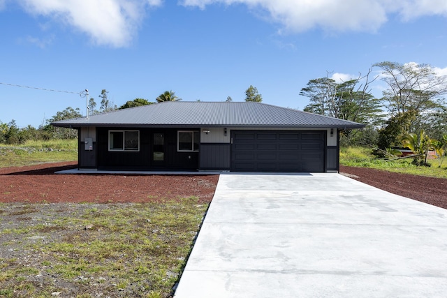 ranch-style home featuring metal roof, driveway, and an attached garage