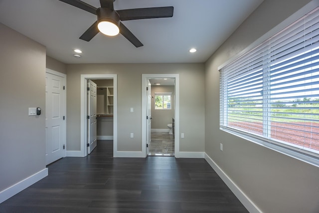 interior space with a spacious closet, baseboards, dark wood-type flooring, and recessed lighting