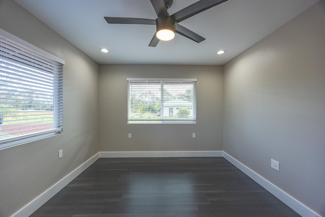 unfurnished room featuring dark wood-style floors, a wealth of natural light, and baseboards