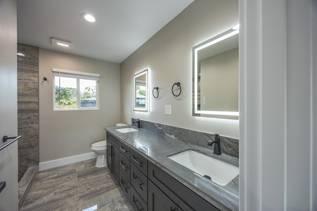 full bathroom featuring double vanity, a sink, toilet, and baseboards