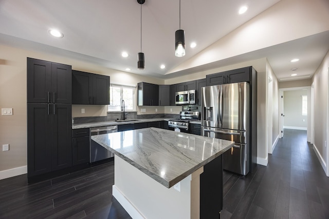 kitchen featuring lofted ceiling, a center island, light stone countertops, stainless steel appliances, and a sink