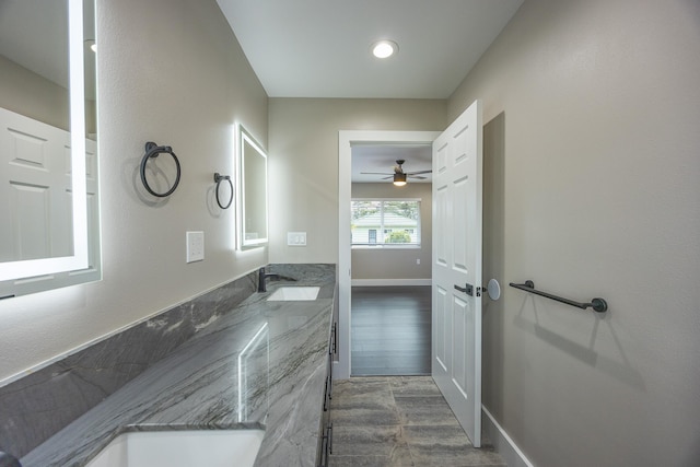 bathroom with double vanity, wood finished floors, a sink, and baseboards