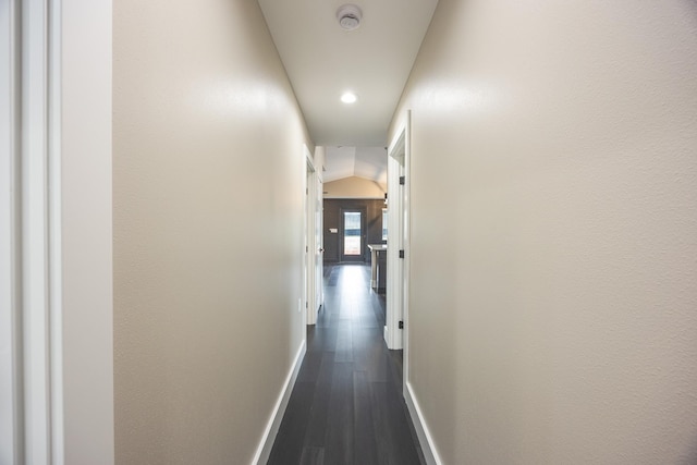 hall featuring dark wood-style flooring and baseboards