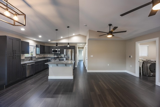 kitchen featuring a breakfast bar, dark wood finished floors, stainless steel appliances, lofted ceiling, and washing machine and dryer