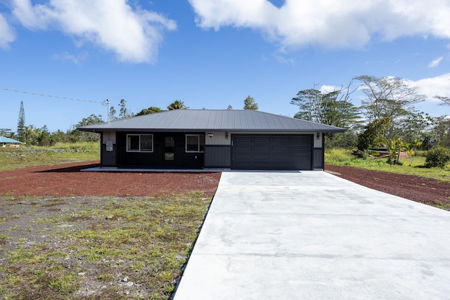 view of front facade with a garage, concrete driveway, and metal roof