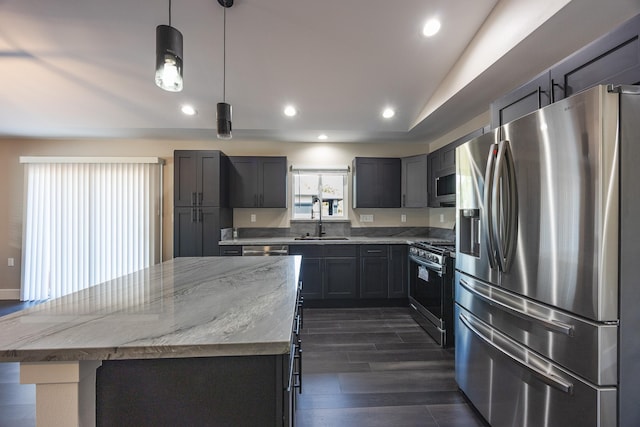 kitchen featuring light stone counters, a center island, stainless steel appliances, dark wood-type flooring, and a sink