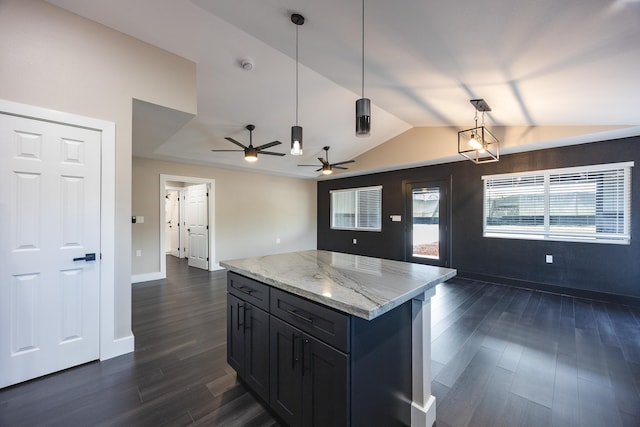 kitchen with dark wood-type flooring, open floor plan, hanging light fixtures, and light stone counters