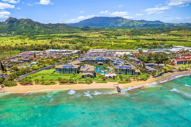 drone / aerial view with a water and mountain view and a view of the beach